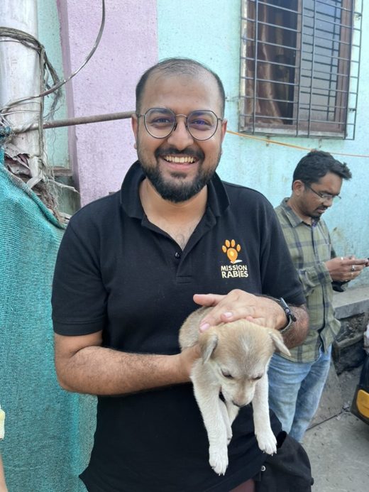 Dr Balaji Chandrashekar, Director of Vet 24-7 India, holding a puppy in the field